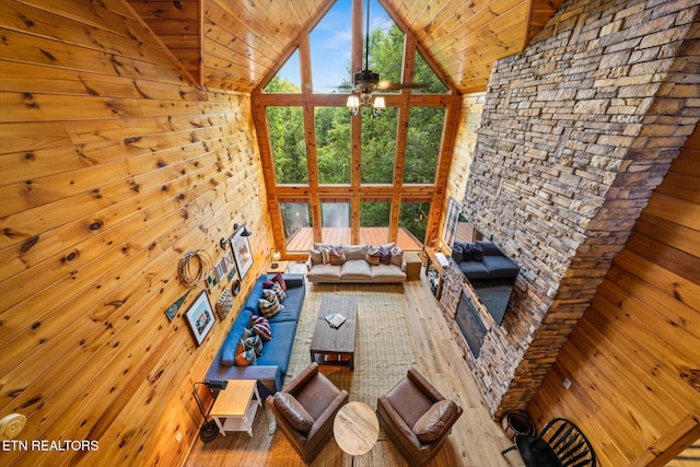 unfurnished living room featuring wooden ceiling, ceiling fan, wood finished floors, wood walls, and high vaulted ceiling