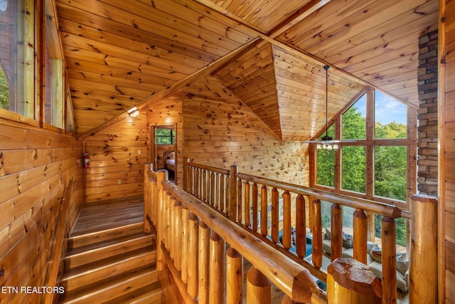 stairway featuring lofted ceiling, wooden ceiling, and wooden walls