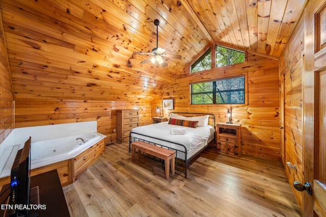 bedroom with wooden walls, vaulted ceiling, and light wood-style flooring