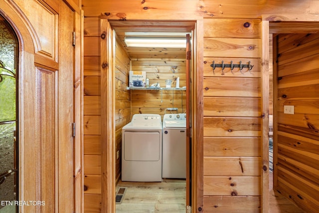 washroom featuring laundry area, separate washer and dryer, wood walls, visible vents, and light wood finished floors