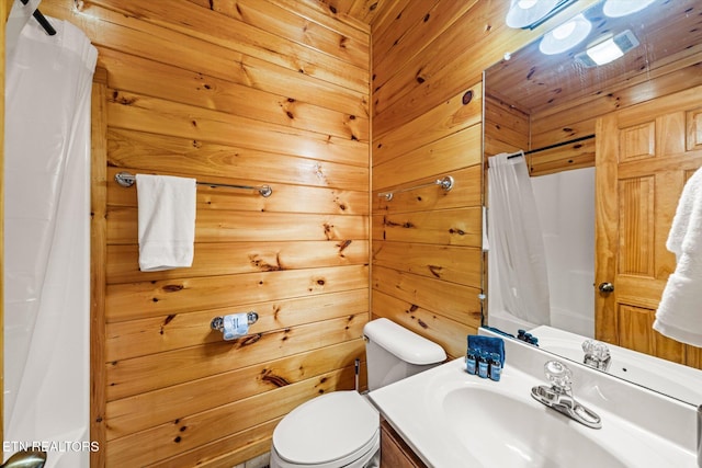 full bath with curtained shower, wood walls, vanity, and toilet