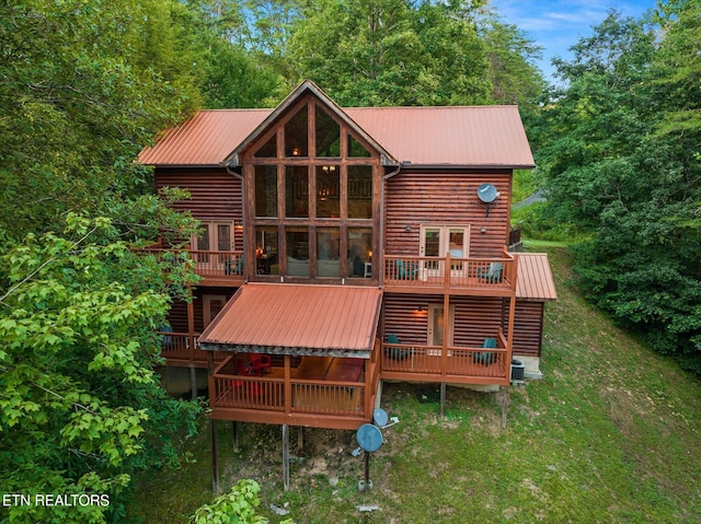 back of house featuring faux log siding, metal roof, and a deck