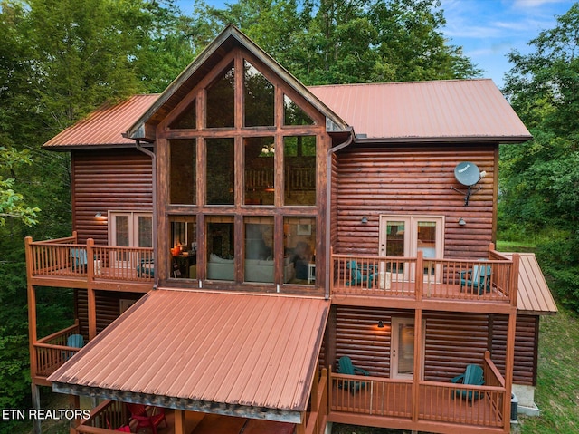 rear view of house with metal roof, log veneer siding, and a wooden deck