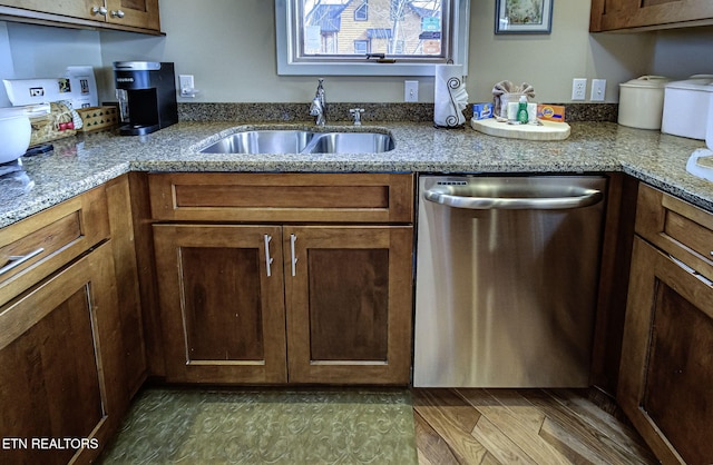 kitchen with a sink, stainless steel dishwasher, and light stone countertops