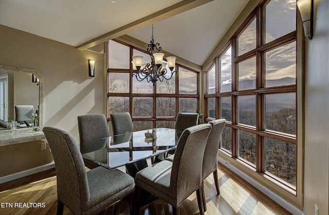 interior space featuring lofted ceiling with beams, hardwood / wood-style floors, an inviting chandelier, a wall of windows, and baseboards