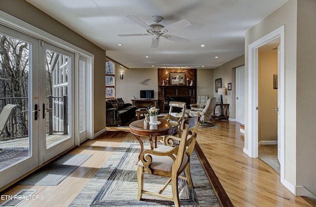 dining space with french doors, a fireplace, light wood-style flooring, and recessed lighting