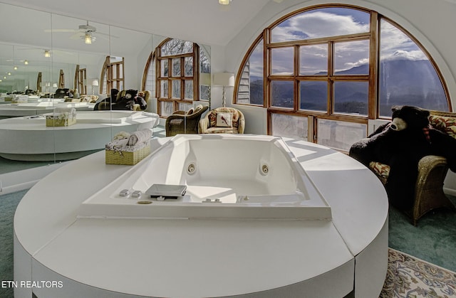 bathroom featuring vaulted ceiling, a tub with jets, and vanity