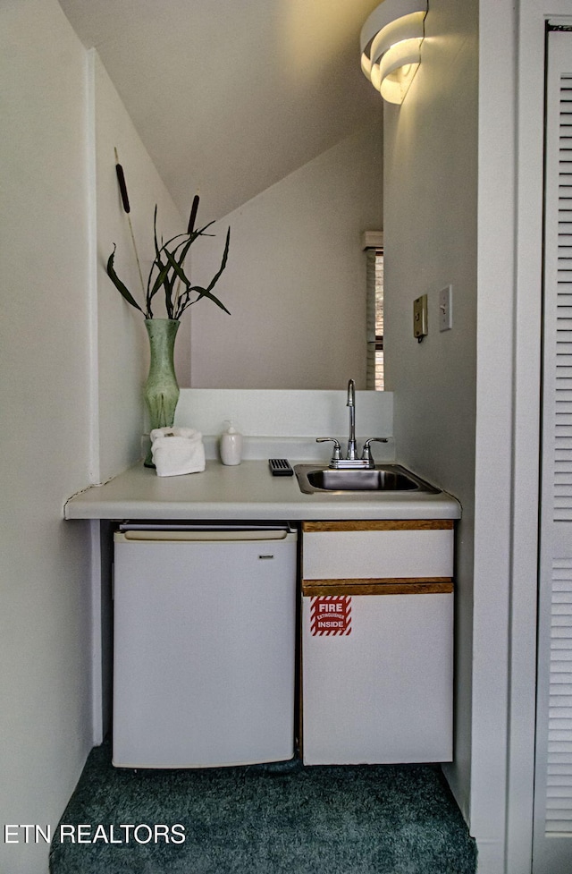 interior space with lofted ceiling, dishwashing machine, light countertops, and a sink