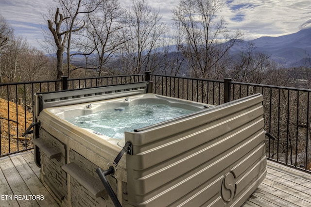 deck featuring a hot tub and a mountain view