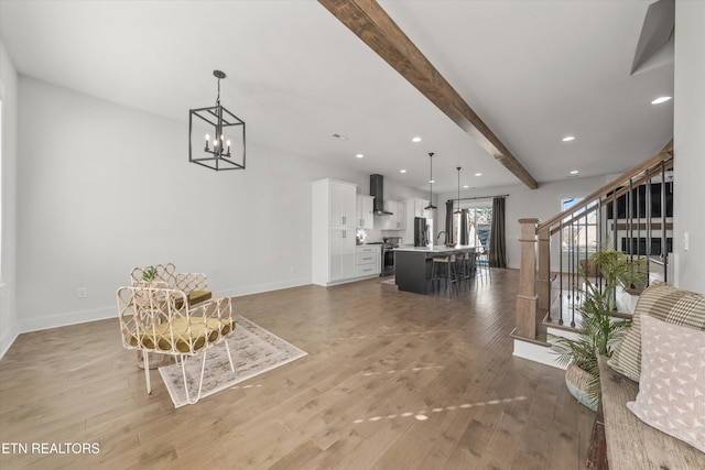 entryway featuring a chandelier, beam ceiling, baseboards, and light wood-style flooring