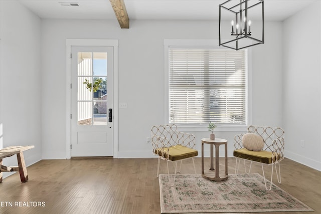 living area with beam ceiling, baseboards, and wood finished floors