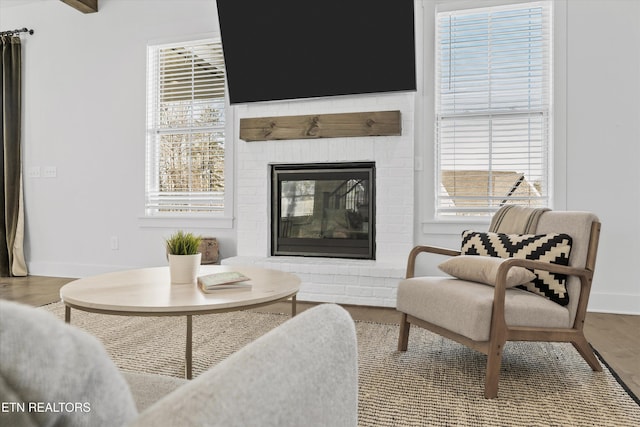 living room with a brick fireplace, wood finished floors, and baseboards