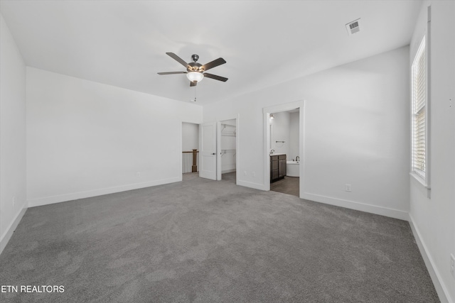 unfurnished bedroom with a spacious closet, visible vents, baseboards, carpet floors, and ensuite bathroom