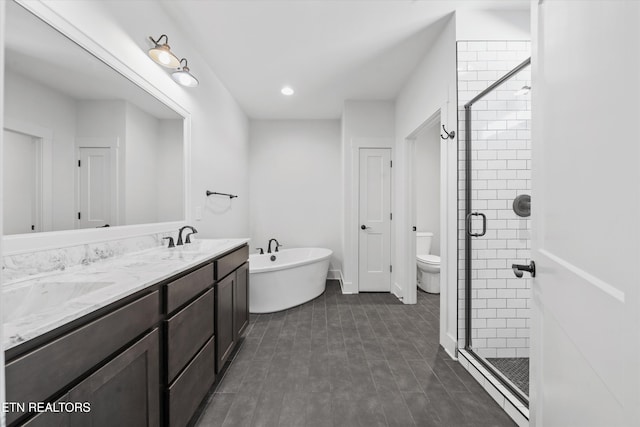 full bath featuring double vanity, a freestanding tub, a sink, a shower stall, and toilet