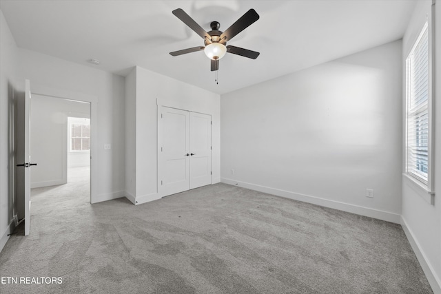 unfurnished bedroom with a closet, baseboards, a ceiling fan, and carpet flooring