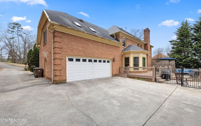 view of front facade featuring a garage, concrete driveway, brick siding, and fence