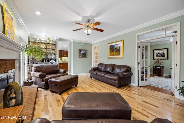 living room featuring ornamental molding, light wood-style flooring, and baseboards