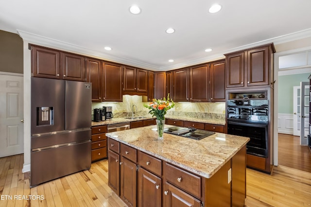 kitchen with black appliances, light wood-style flooring, ornamental molding, and a sink