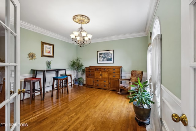 interior space featuring a chandelier, wainscoting, crown molding, and wood finished floors