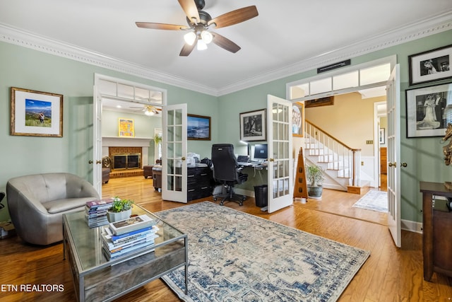 living room featuring french doors, a fireplace, stairway, ornamental molding, and wood finished floors