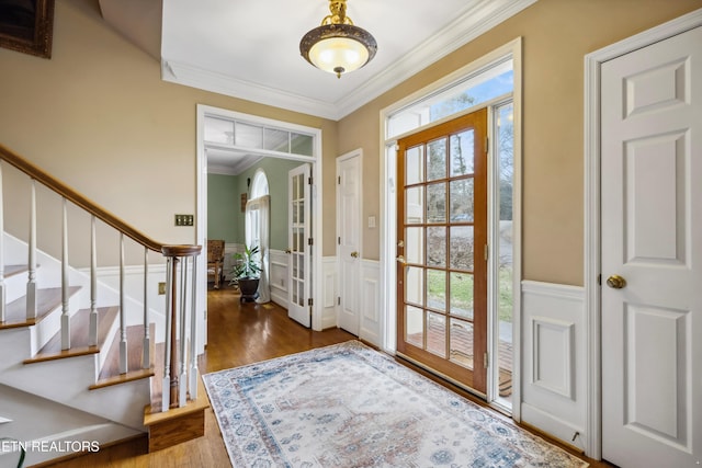 foyer entrance with wainscoting, wood finished floors, a wealth of natural light, and crown molding