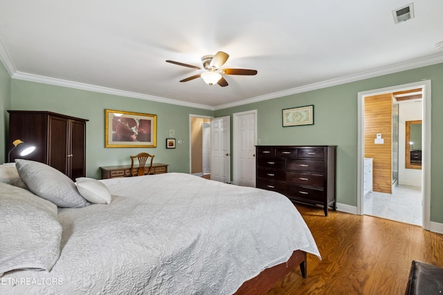 bedroom featuring ornamental molding, visible vents, baseboards, and wood finished floors