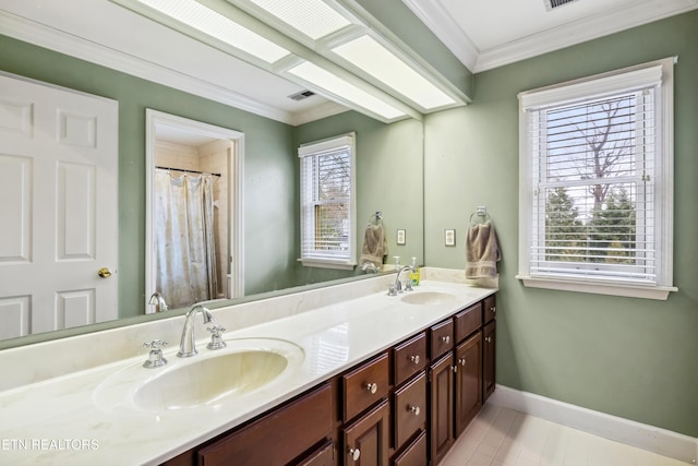 full bathroom with double vanity, ornamental molding, a sink, and baseboards