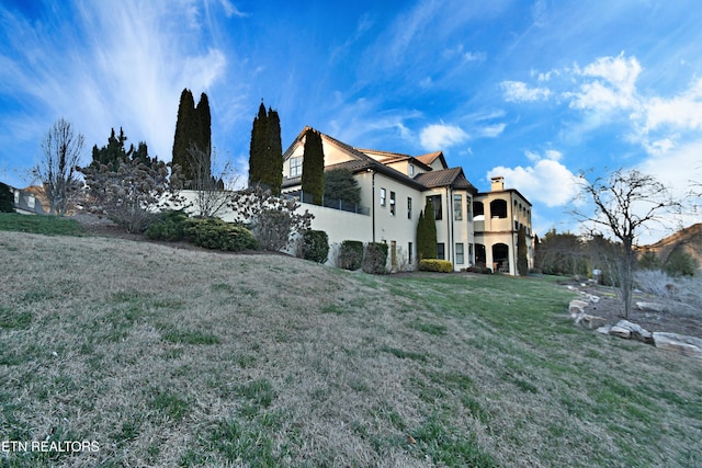 view of side of property with a lawn and a chimney