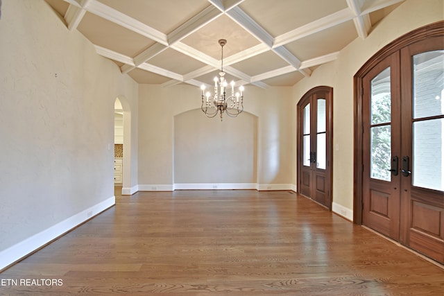 foyer entrance with french doors, arched walkways, coffered ceiling, and wood finished floors