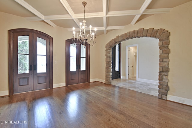 entrance foyer with arched walkways, french doors, and wood finished floors