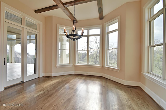 unfurnished dining area featuring beamed ceiling, baseboards, a healthy amount of sunlight, and wood finished floors