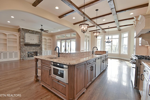 kitchen featuring a sink, appliances with stainless steel finishes, a center island with sink, and a fireplace