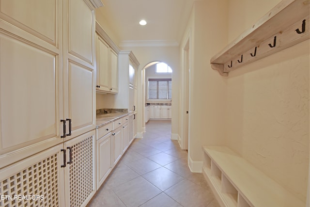 mudroom with ornamental molding, recessed lighting, arched walkways, light tile patterned floors, and baseboards