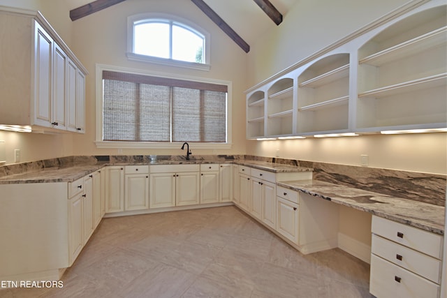 kitchen featuring light stone counters, a sink, vaulted ceiling with beams, and open shelves