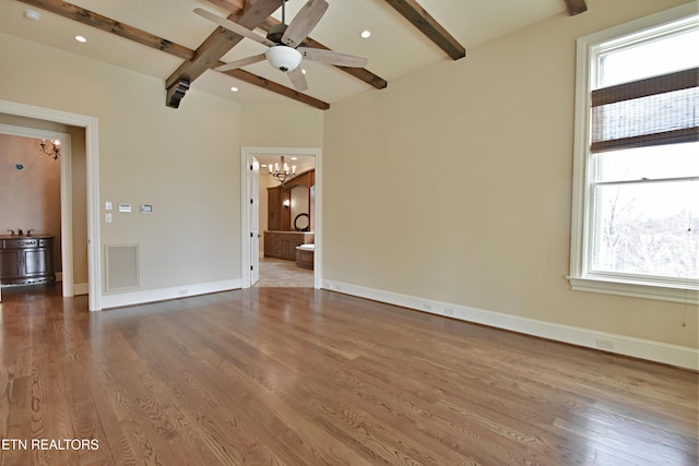 unfurnished room with visible vents, beam ceiling, plenty of natural light, and wood finished floors