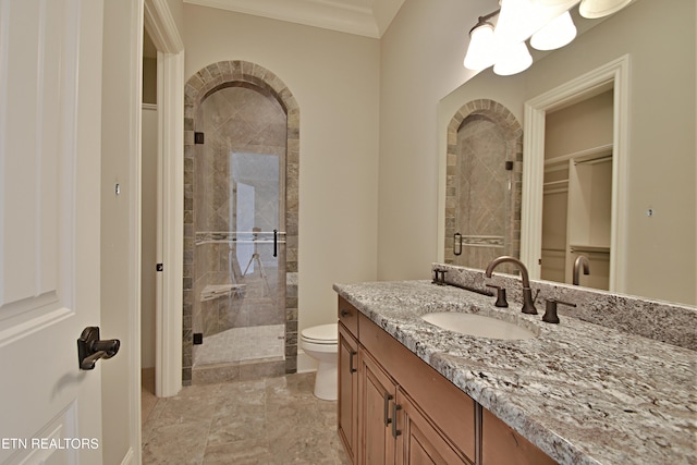 bathroom with vanity, toilet, a stall shower, and ornamental molding