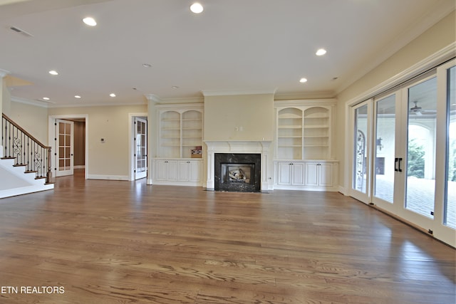 unfurnished living room with wood finished floors, baseboards, recessed lighting, a high end fireplace, and ornamental molding