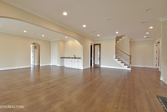 empty room with baseboards, stairway, recessed lighting, wood finished floors, and arched walkways