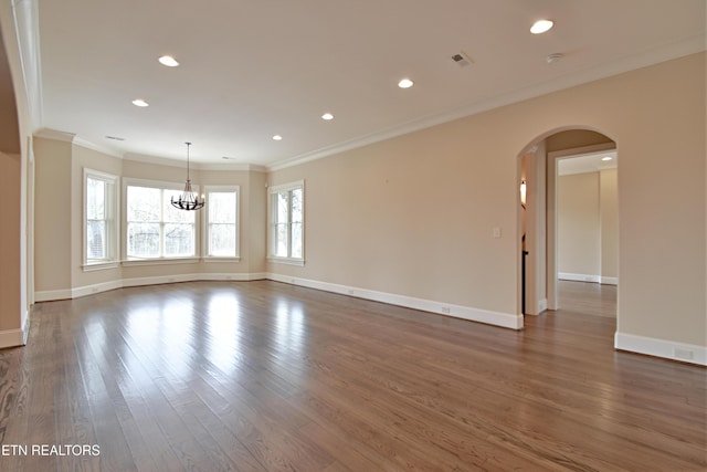 spare room featuring wood finished floors, recessed lighting, arched walkways, crown molding, and baseboards