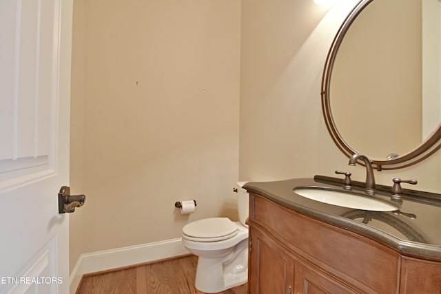 bathroom featuring toilet, vanity, baseboards, and wood finished floors