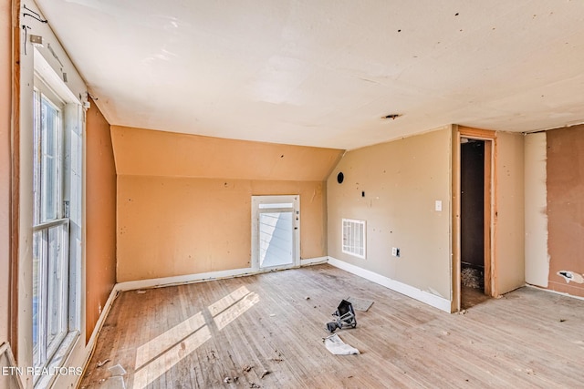 additional living space with light wood finished floors, visible vents, vaulted ceiling, and a wealth of natural light