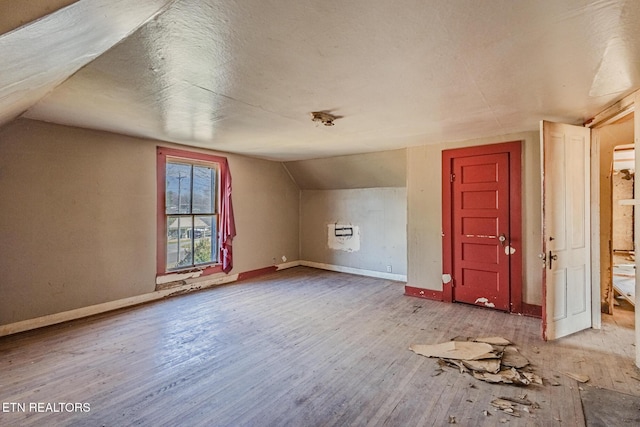 additional living space with lofted ceiling, a textured ceiling, baseboards, and wood finished floors