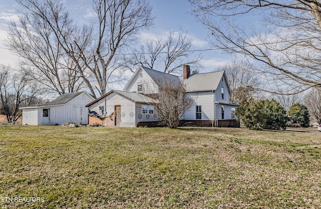 view of front of house with an outbuilding, a front lawn, and a chimney