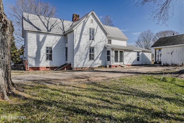 back of house featuring entry steps, crawl space, metal roof, and a chimney