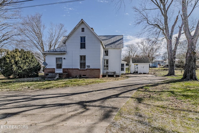 view of side of home with entry steps, metal roof, and brick siding