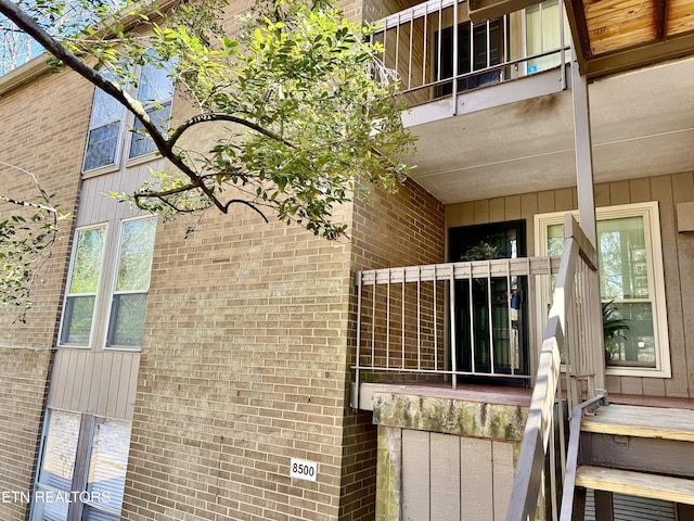 view of property exterior featuring brick siding and a balcony