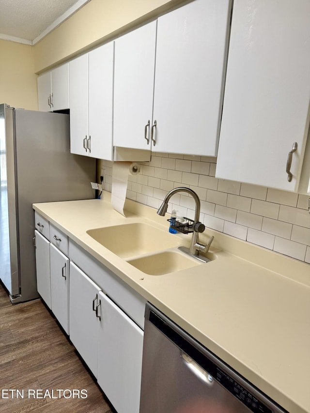 kitchen featuring dark wood-style flooring, light countertops, appliances with stainless steel finishes, white cabinets, and a sink