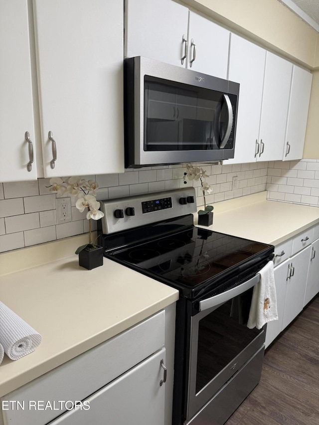 kitchen featuring stainless steel appliances, white cabinetry, backsplash, and dark wood-type flooring