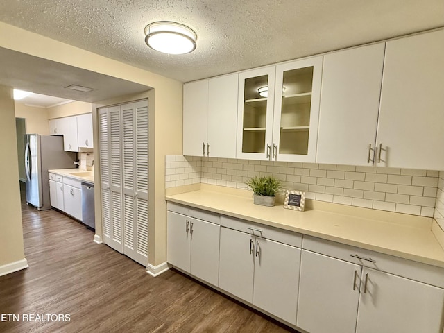 kitchen with white cabinets, appliances with stainless steel finishes, dark wood finished floors, and light countertops