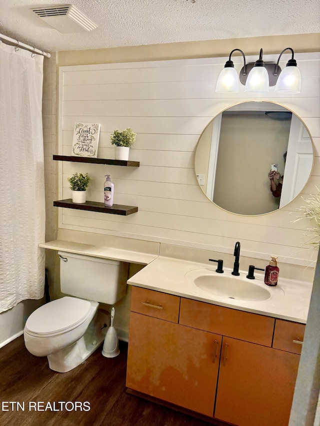 full bath with visible vents, toilet, vanity, a textured ceiling, and wood finished floors